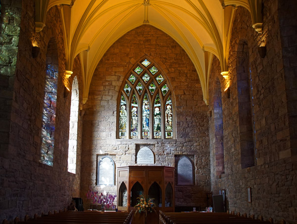 interior of a stone church with tall stained glass windows and wooden altar showcasing beautiful architectural details in a serene setting ideal for reflection and worship 2 stunning features