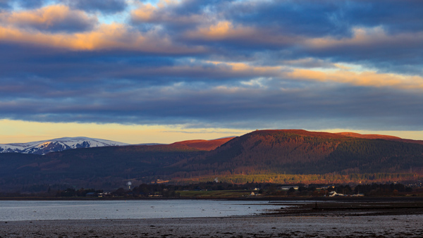 mountainous landscape with colorful sunset reflections over calm waters and a serene sky featuring scattered clouds ideal for nature photography and outdoor adventure