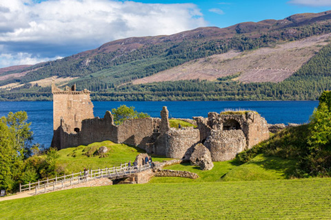 historic ruins of a castle by the lake with lush green grass and mountains in the background featuring seven towers and seven wonders of nature