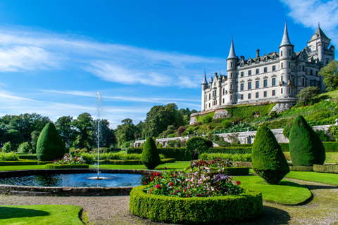 stunning castle surrounded by landscaped gardens and fountain showcasing two vibrant flower beds